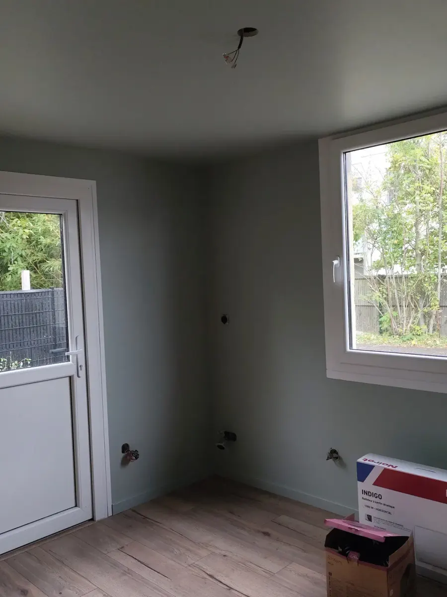 Bureau après travaux : murs gris-vert clair, plafond clair, sol stratifié chêne, porte vitrée et fenêtre blanches