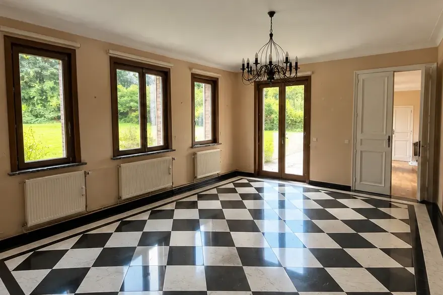 La même pièce, plafond repris : murs beiges et menuiseries en bois foncé encore à peindre