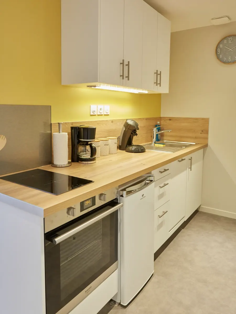 Cuisine aux meubles blancs dont le mur de crédence est peint en jaune vif