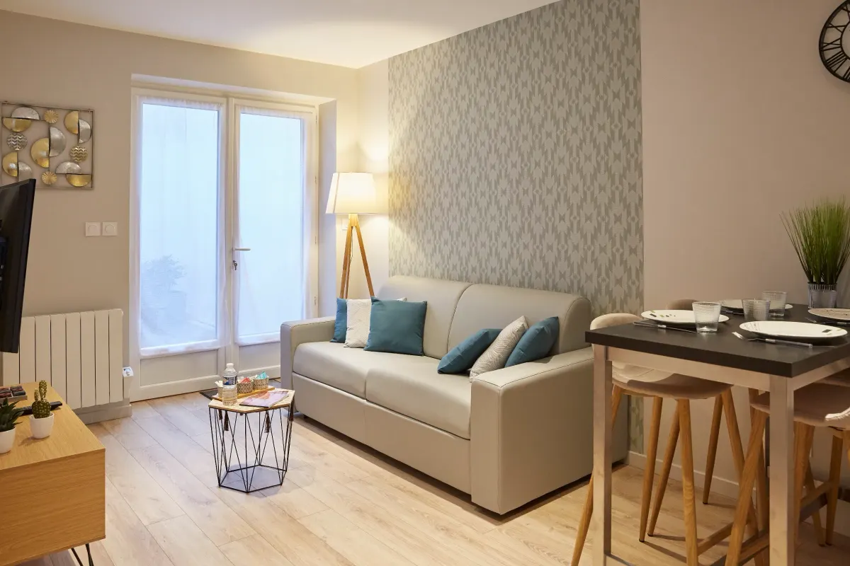 Salon dont le mur du fond est tendu d’un papier peint damassé gris, murs latéraux en beige