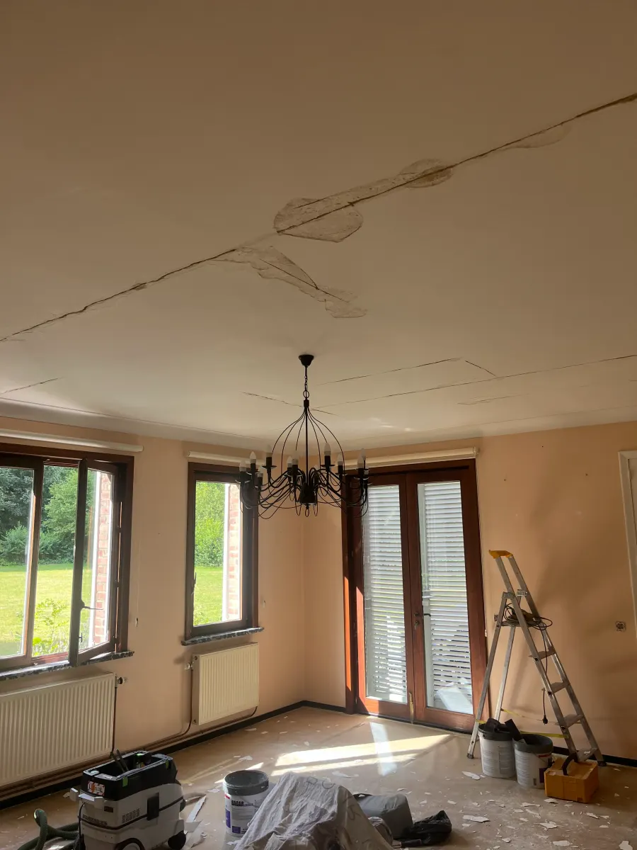 Plafond fissuré en cours de reprise, bandes de calicot apposées et pièce protégée pendant le chantier