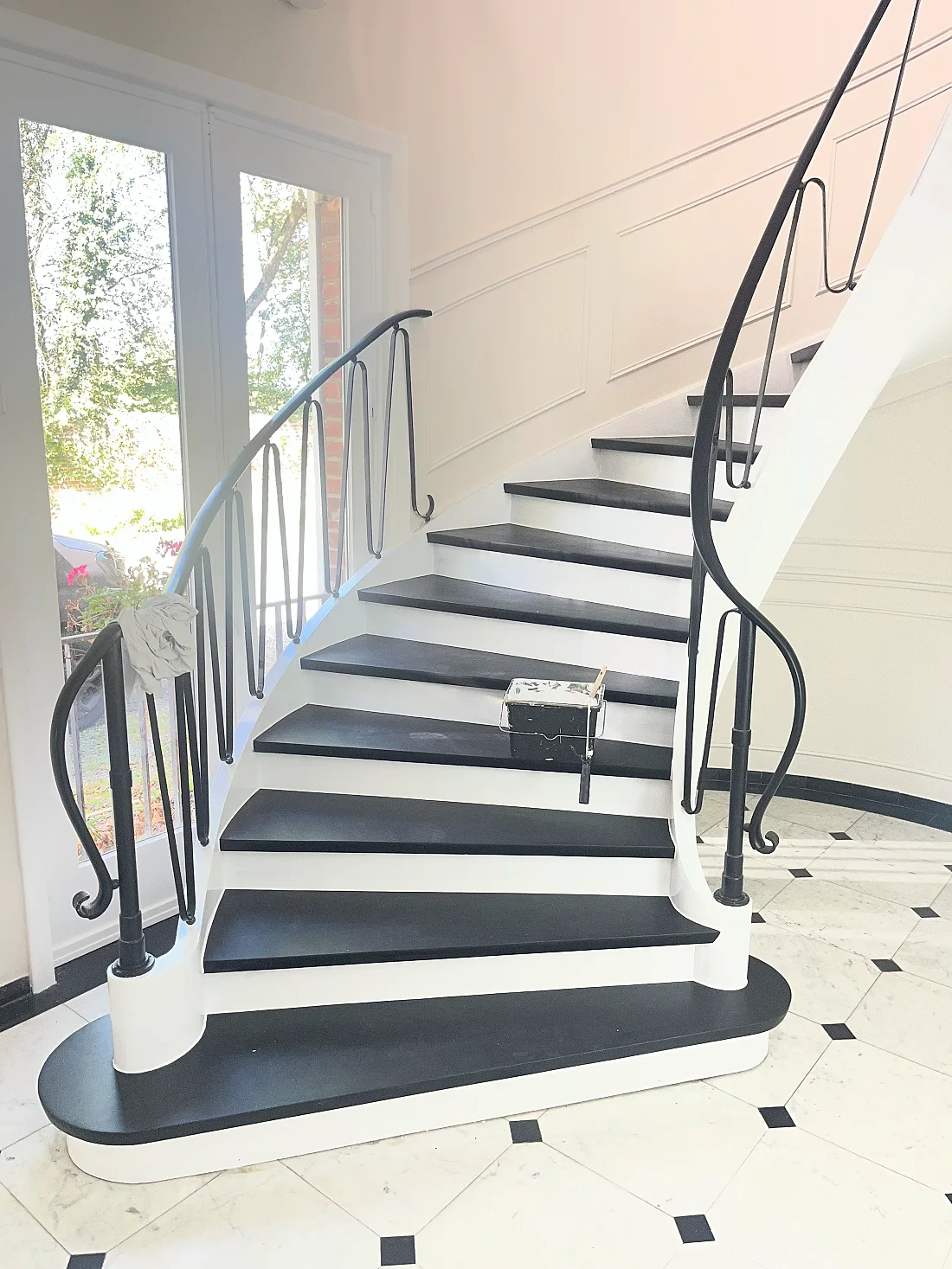 Cage d'escalier rénovée : marches noires, contremarches blanches, rampe en fer forgé conservée