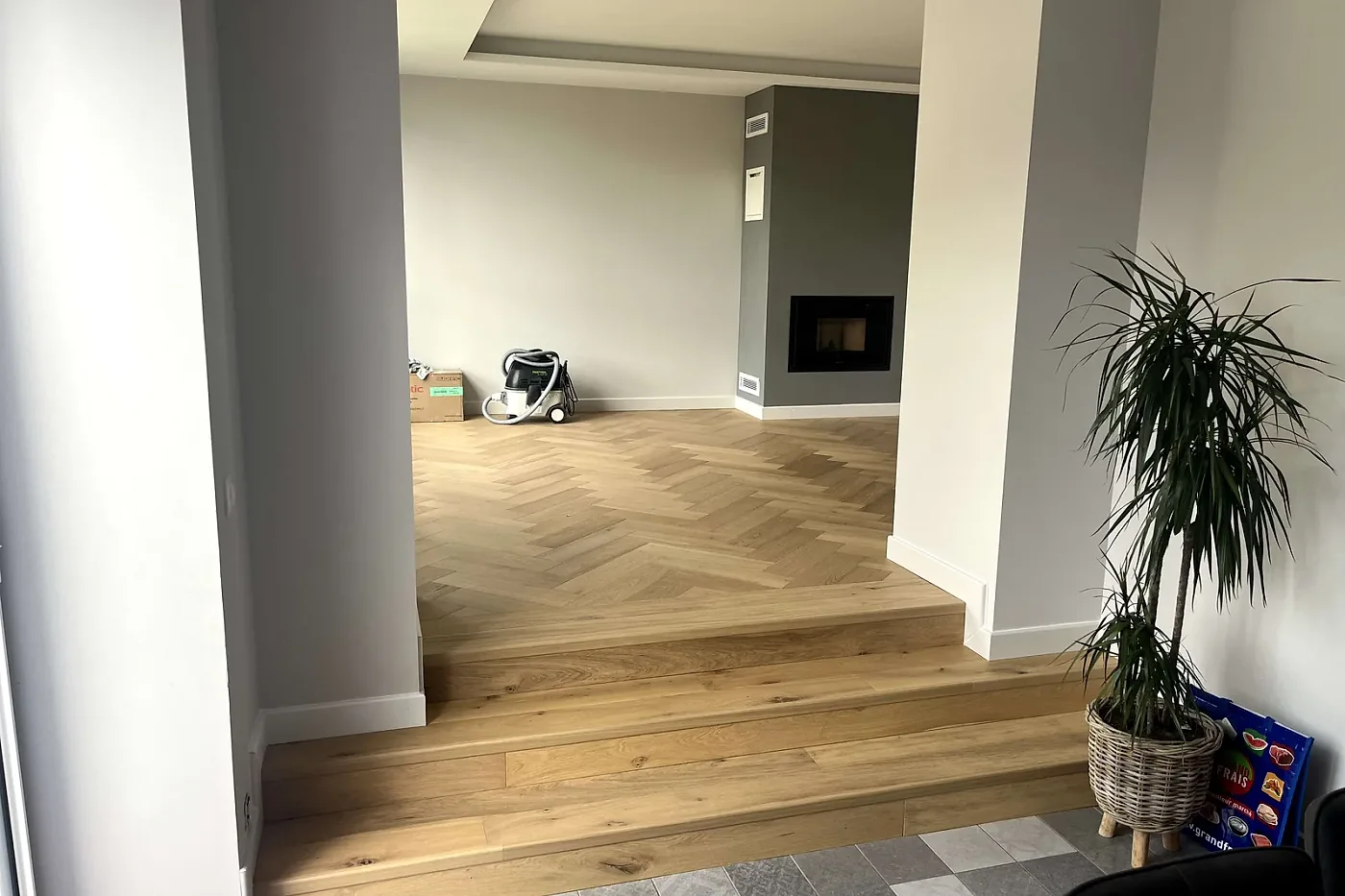 Parquet en chevron chêne clair posé jusque sur les marches, entre deux pièces