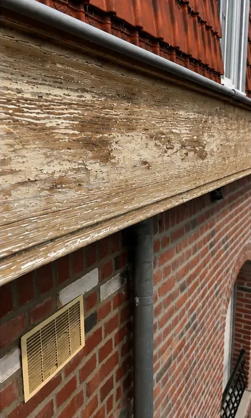 Le même bandeau de rive en cours de décapage : peinture retirée, bois brut à nu