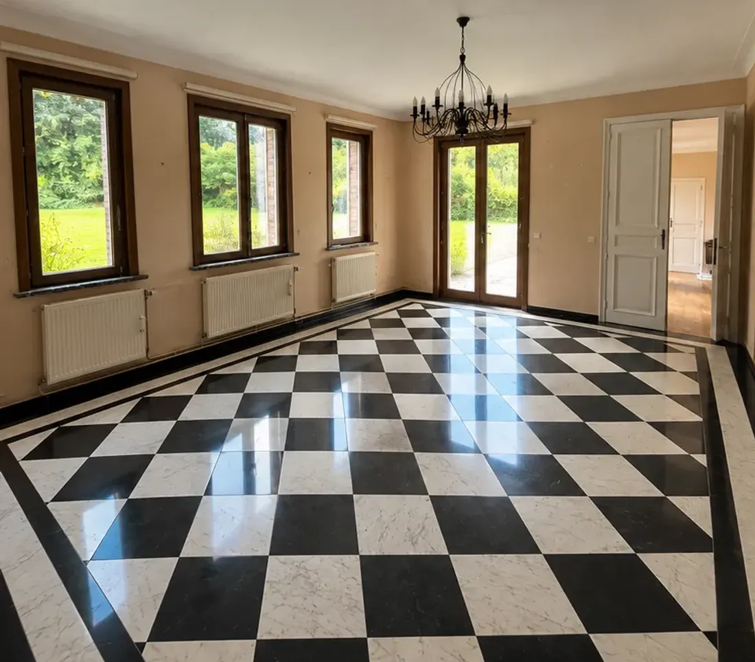 Grande pièce avant travaux : murs beiges, menuiseries et plinthes en bois foncé, sol en damier noir et blanc