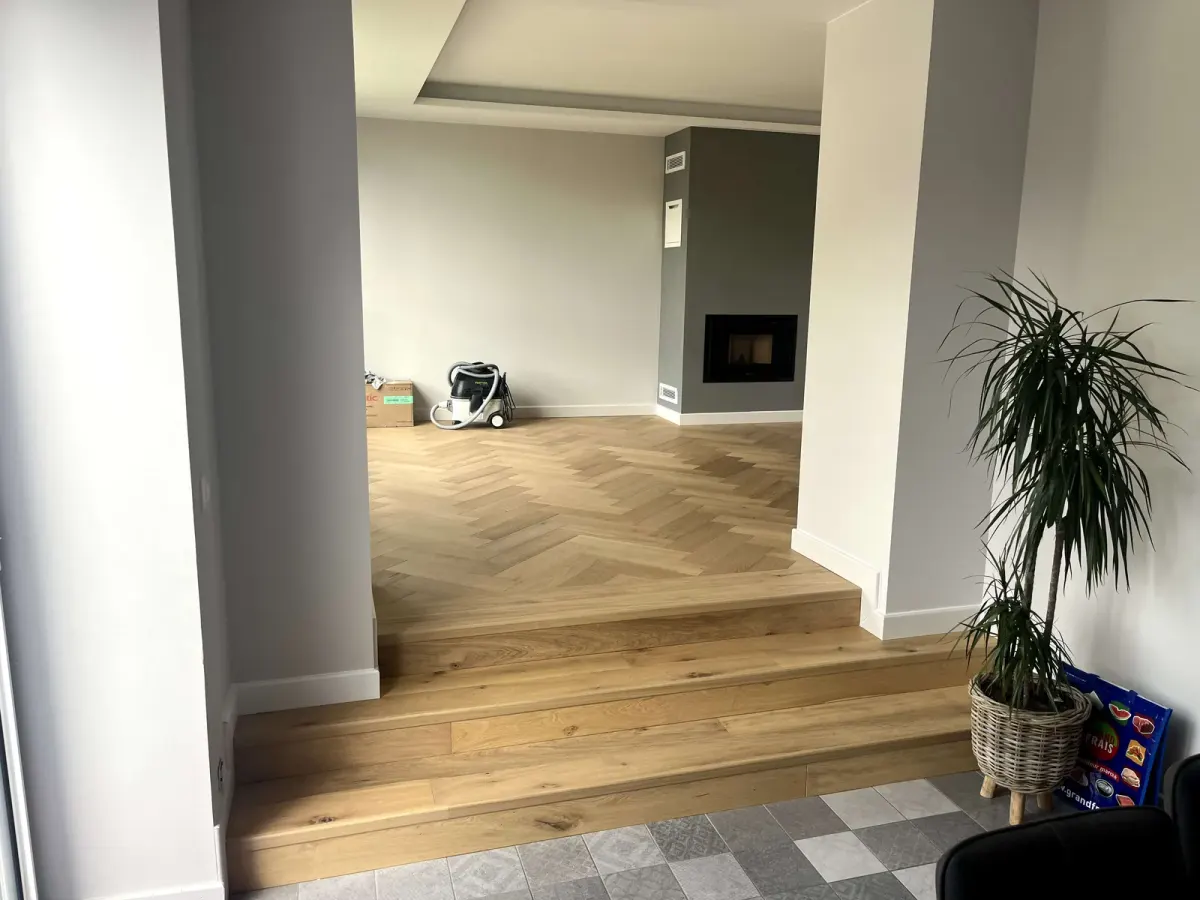 Parquet en chevron chêne clair posé jusque sur les marches, entre deux pièces